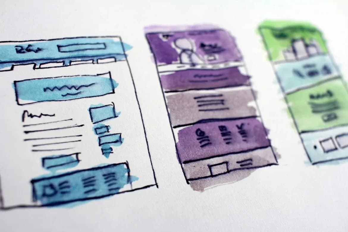 Três layouts de página da web coloridos desenhados em papel
