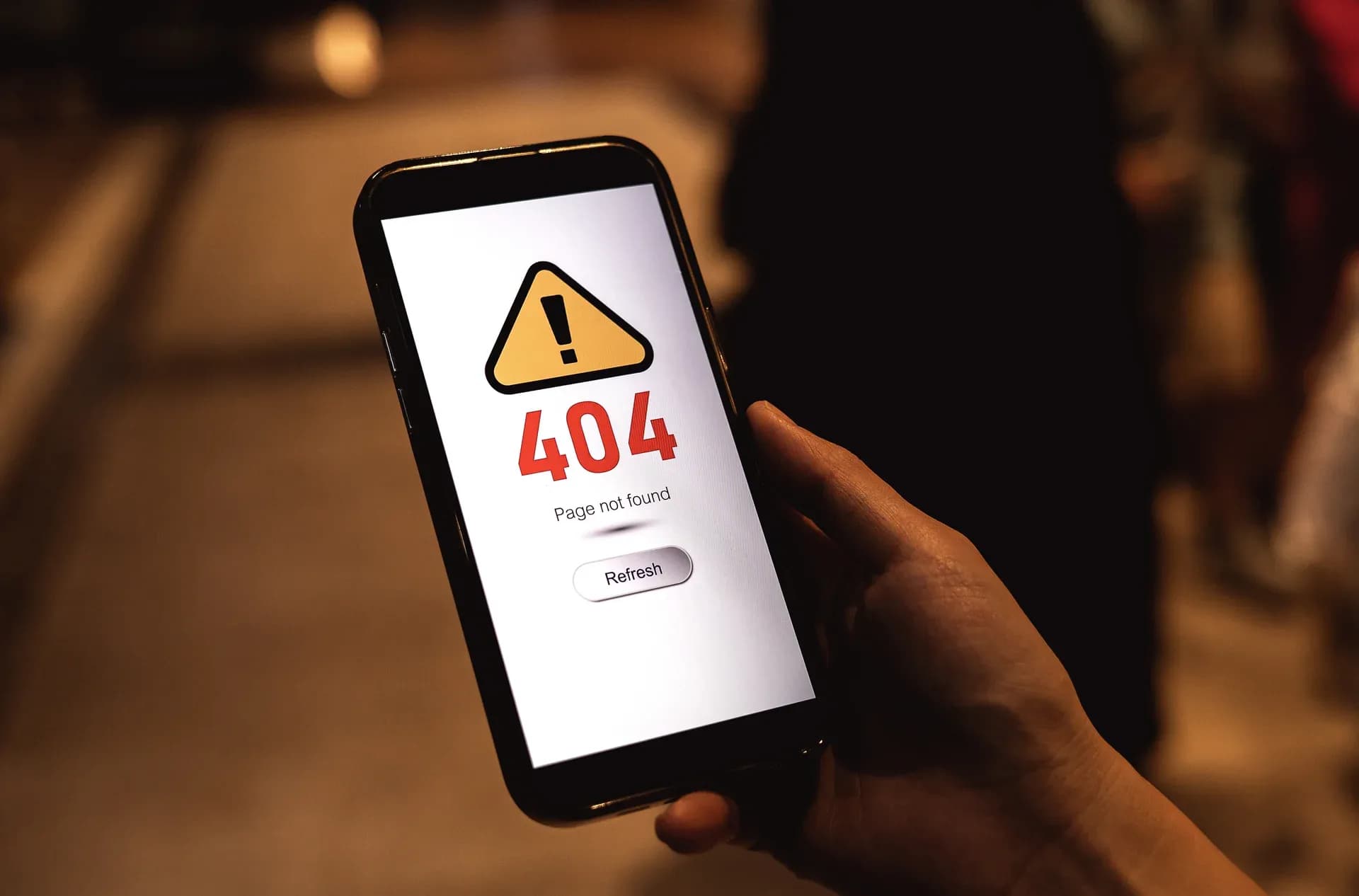 Pessoa segurando celular com mensagem de erro 404 na tela